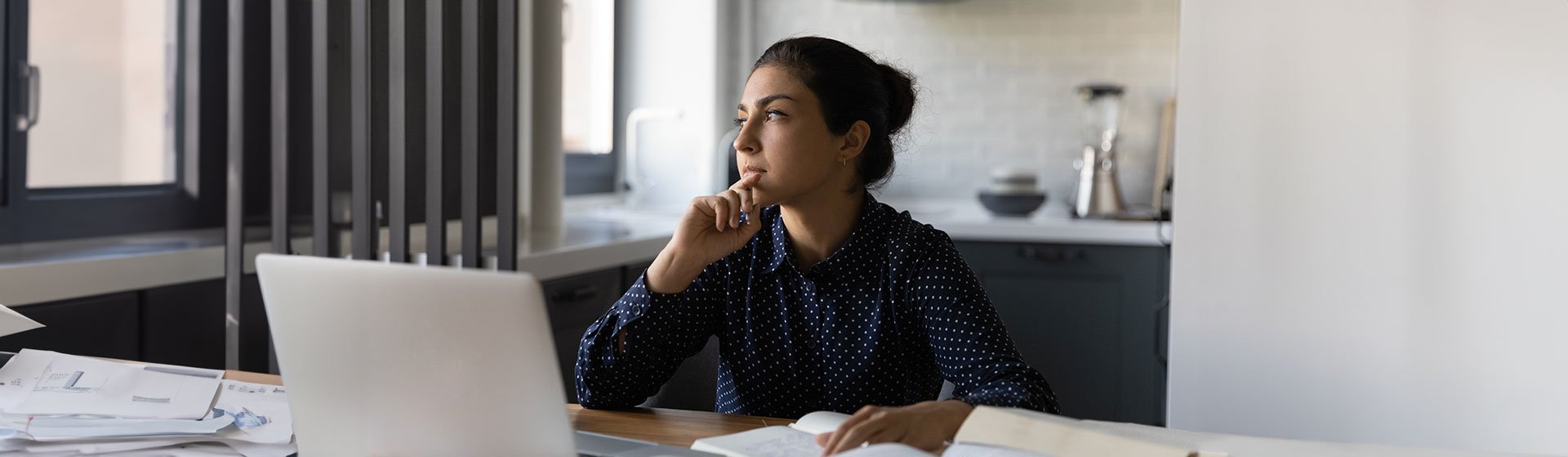 Pensive Indian woman studying online at home, contemplating certified mediator benefits